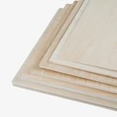 A stack of CrealityFalcon Basswood Plywood Sheets 11.8" x 11.8" for Laser Engraving is arranged in a slightly fanned-out manner. The rectangular panels, with smooth surfaces made of thin, unfinished wood, would be ideal for DIY projects. In this arrangement, the edges of each sheet are clearly visible. Available in packs of 10pcs, 6pcs, and 3pcs.