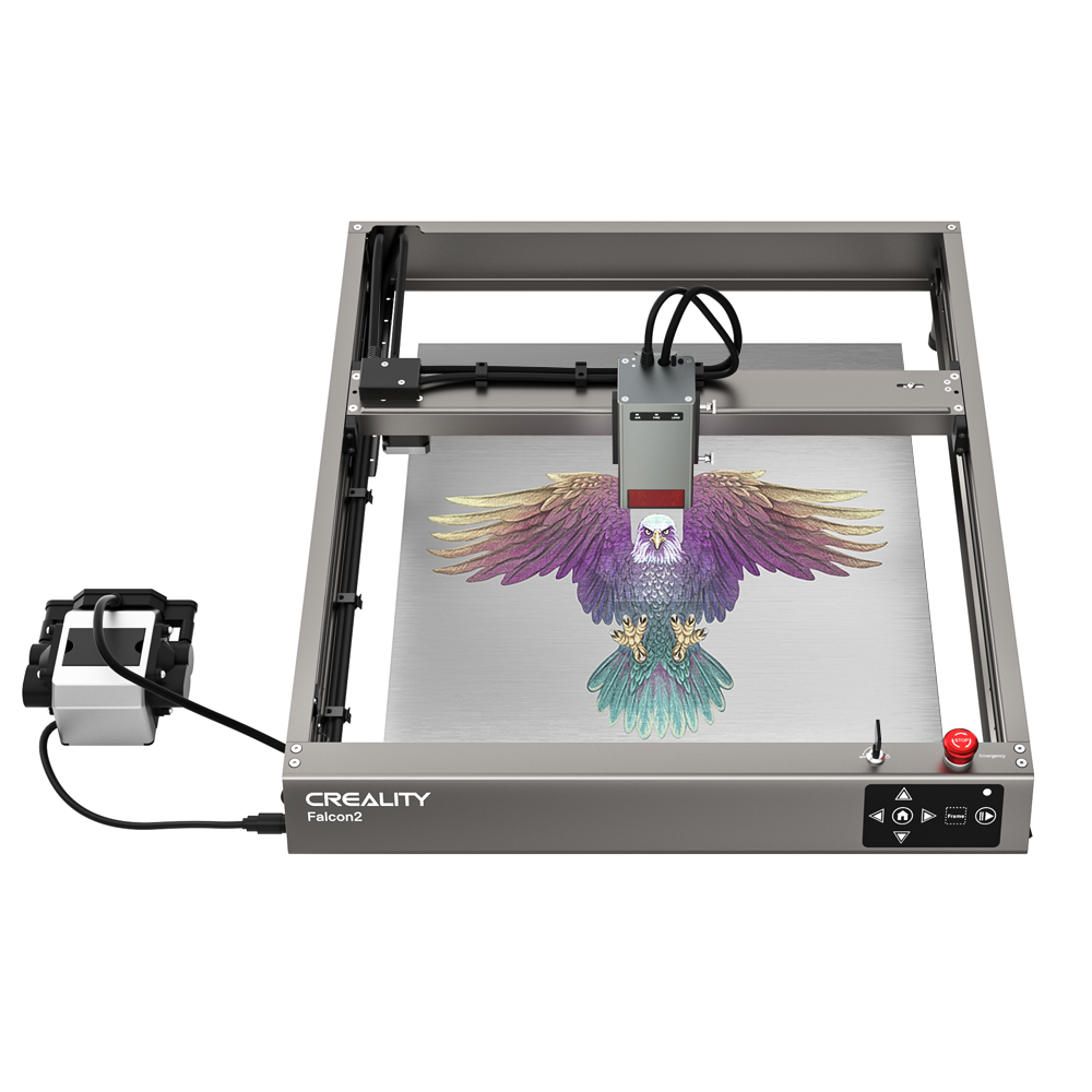 A Falcon2 22W Laser Engraver and Cutter, marked with "Creality Falcon2," meticulously engraves a colorful, detailed image of a phoenix on a flat surface. The rectangular CrealityFalcon machine features visible controls and wiring, with the engraving tool positioned at its center.