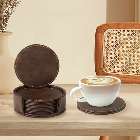 A hand holds a green mug with the text "Lucky" printed on it. The mug is placed near a set of CrealityFalcon Personalised Brown Leather Coasters with Holder for Falcon Home Laser Engraving - 6 PCS, one of which features intricate woodworking laser engraving and is out of the holder on a wooden table. A potted plant with green leaves is in the background.