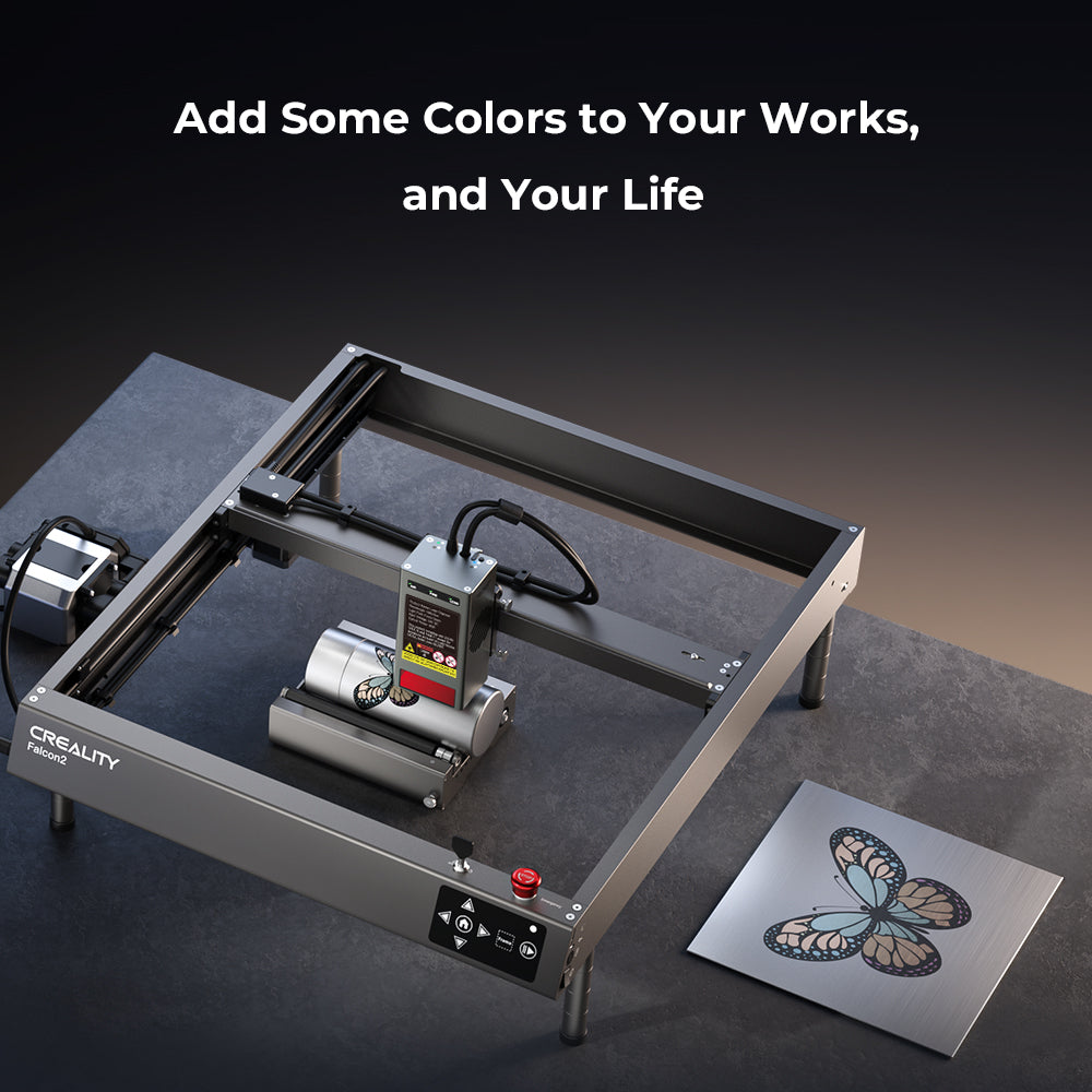 A CrealityFalcon Falcon2 40W Laser Engraver and Cutter is positioned on a dark tabletop next to a metal plate featuring a colorful, intricately engraved butterfly design. Above the engraver, white text reads "Add Some Colors to Your Works and Your Life" with ultra-fast cutting speed.